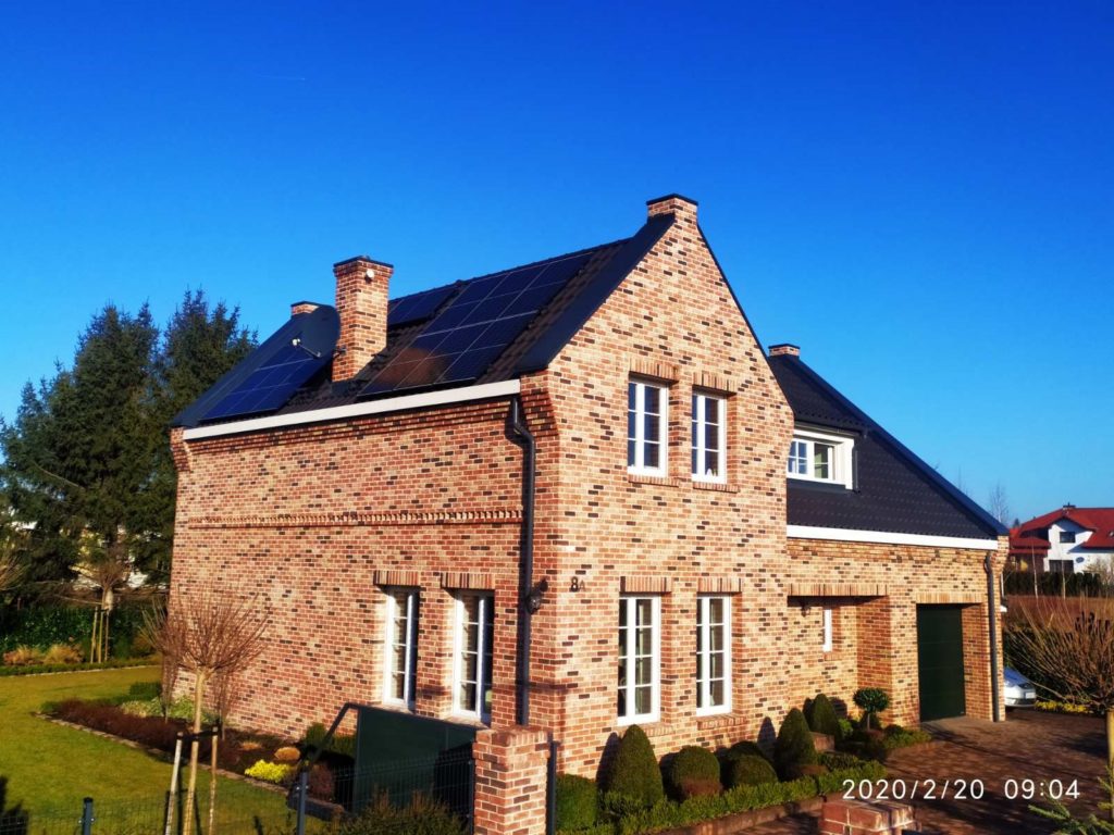 Dom z czerwonej cegły z dachówką z zamontowanymi panelami słonecznymi