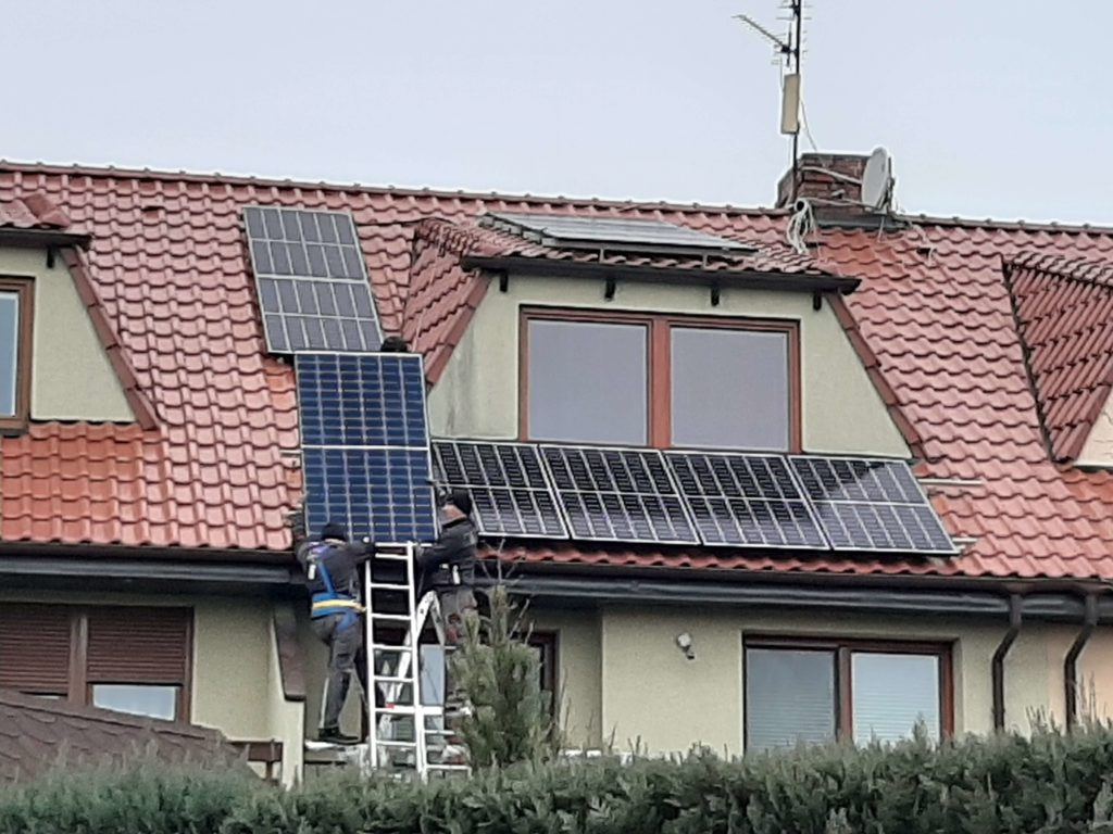 Montaż paneli słonecznych na dachu - Montażyści na drabinie